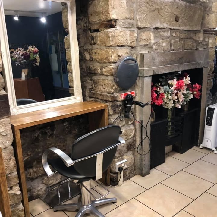 A styling chair beside The Salon’s stone fireplace and framed mirror
